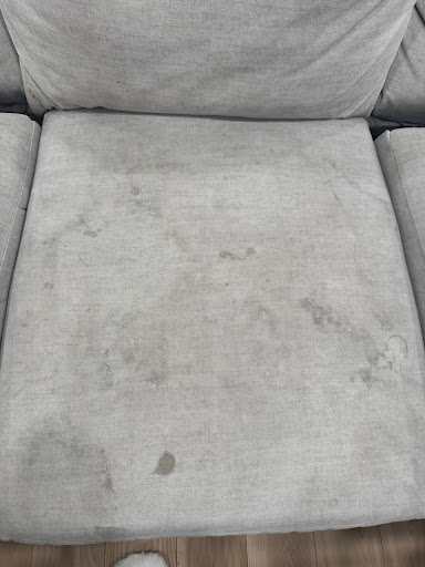 A fabric sofa cushion marked and dulled before cleaning