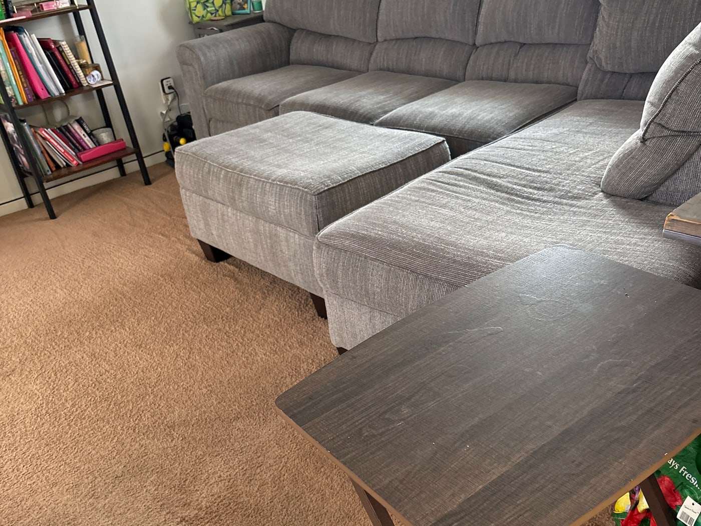 A grey fabric sectional sofa and tan carpet in a lived-in living room after cleaning